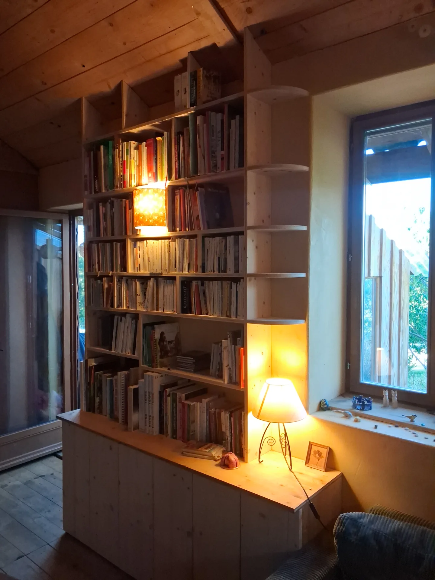 Bespoke bookcase in 3-ply spruce under a sloping ceiling in Gerde, with a light built into the front