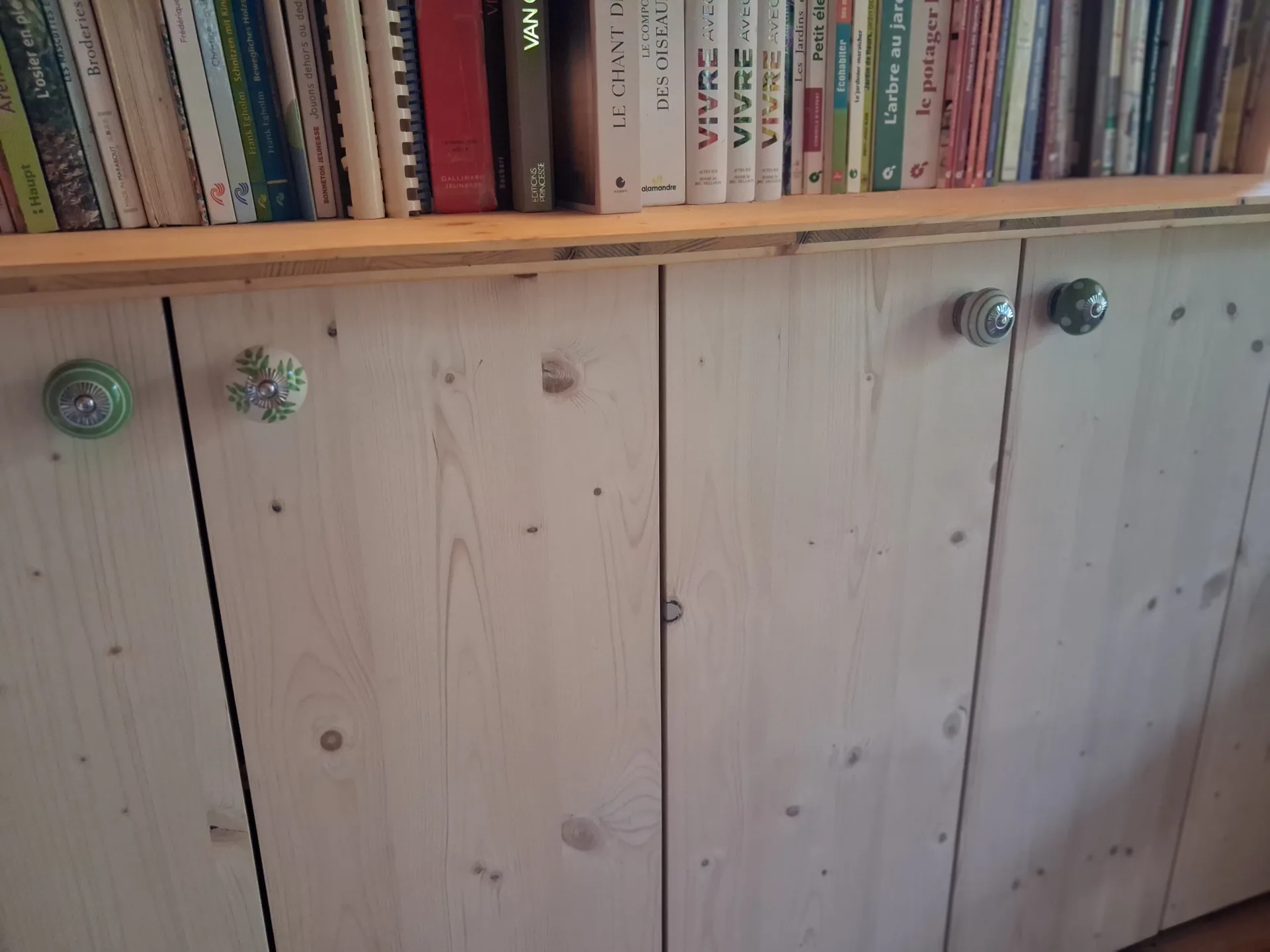 Lower part of the spruce bookcase closed by doors, every door knob different