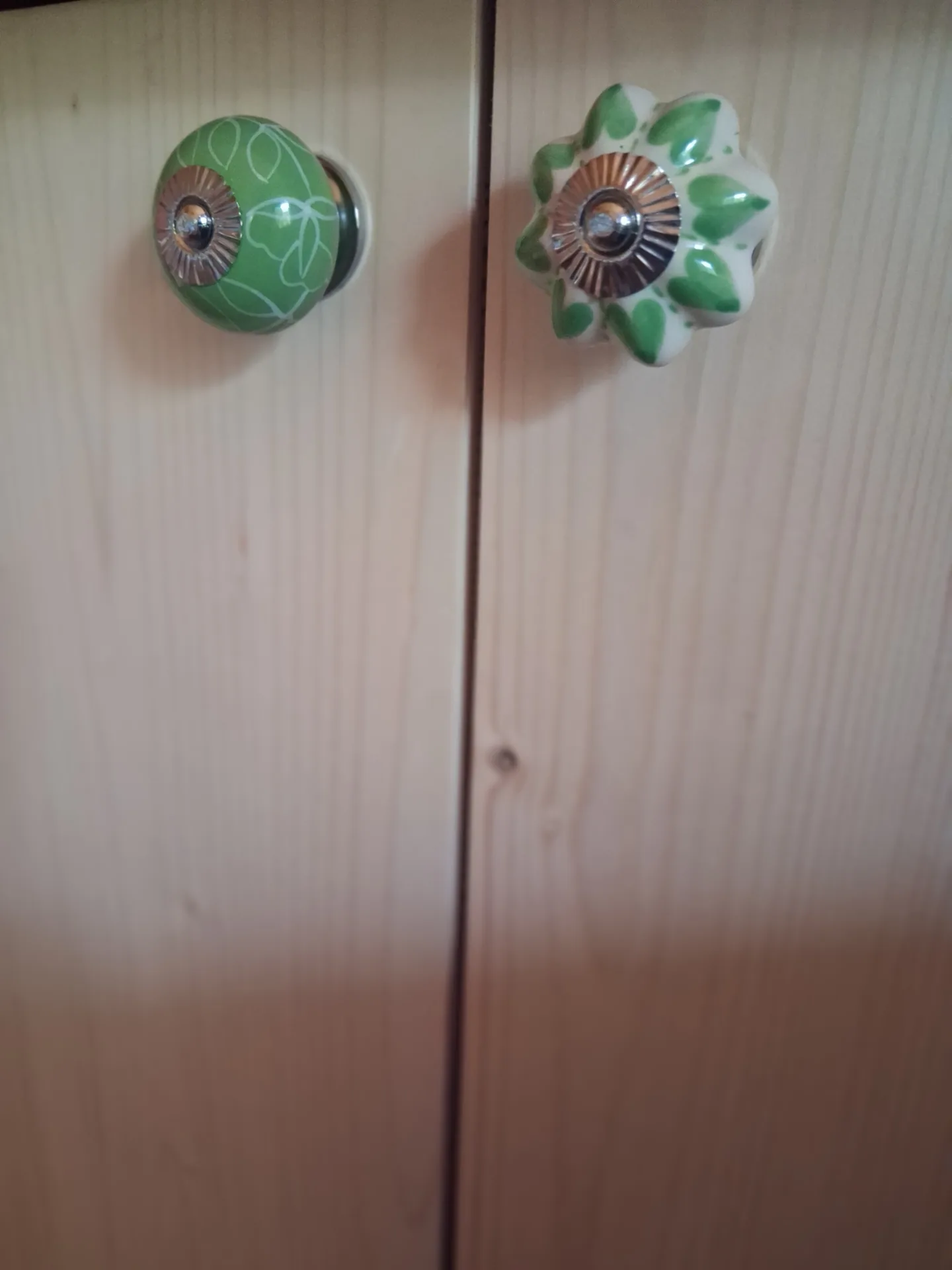 Detail of two mismatched knobs on the spruce doors of the bookcase
