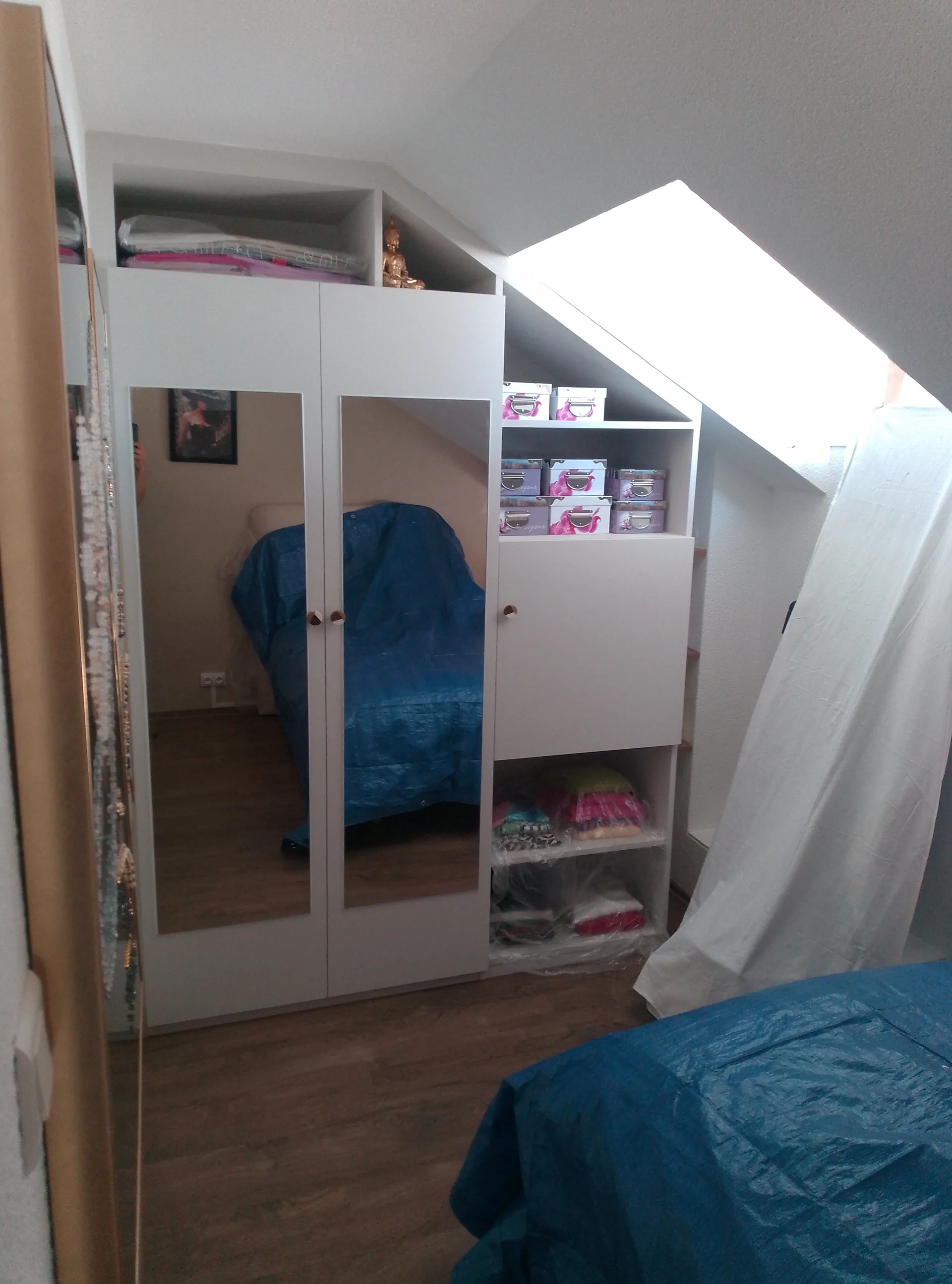 Walk-in wardrobe under the slope with mirrored doors, filled and integrated into the loft bedroom