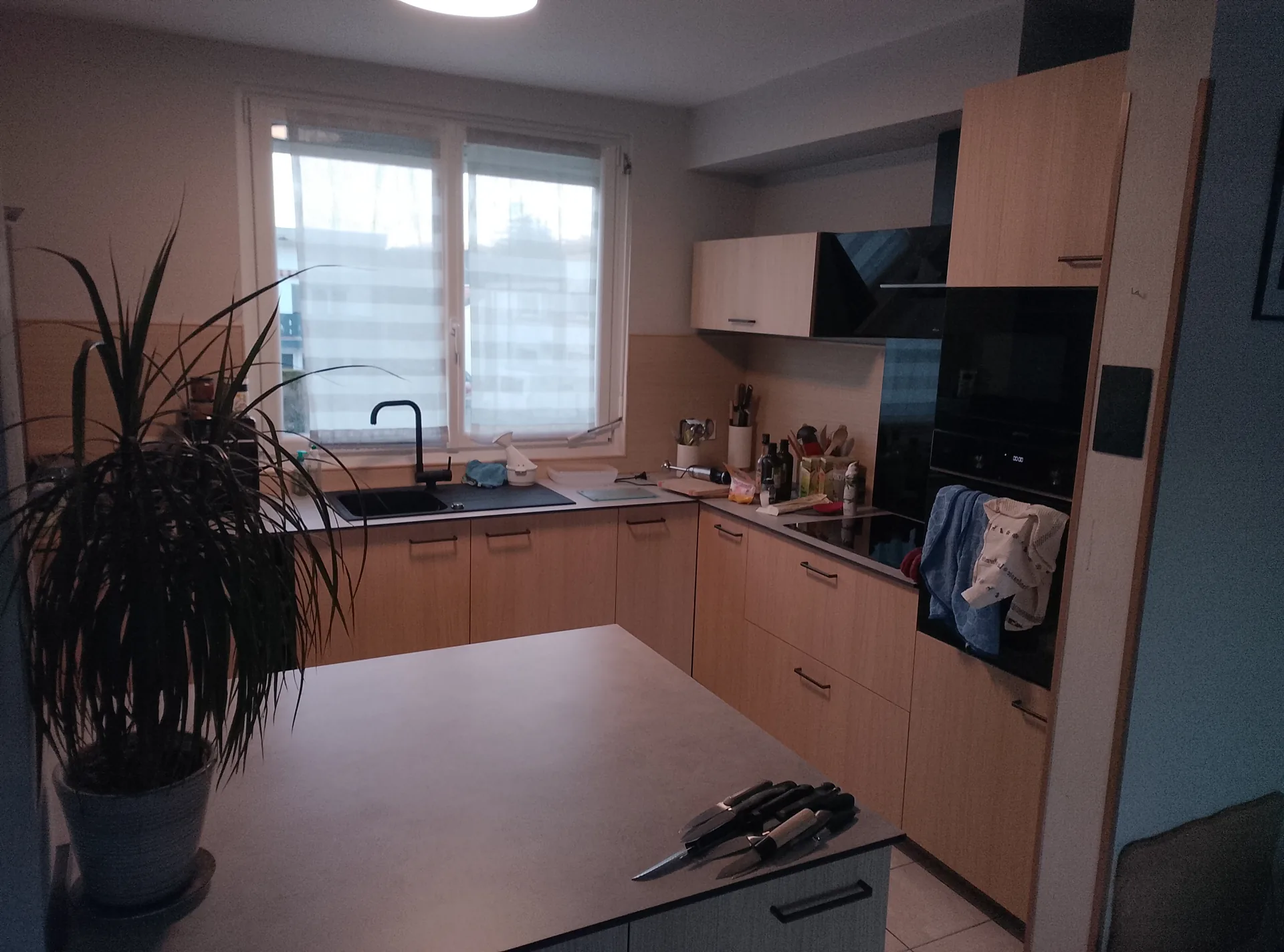 The finished kitchen: oak-effect fronts, black appliances and the concrete-effect worktop