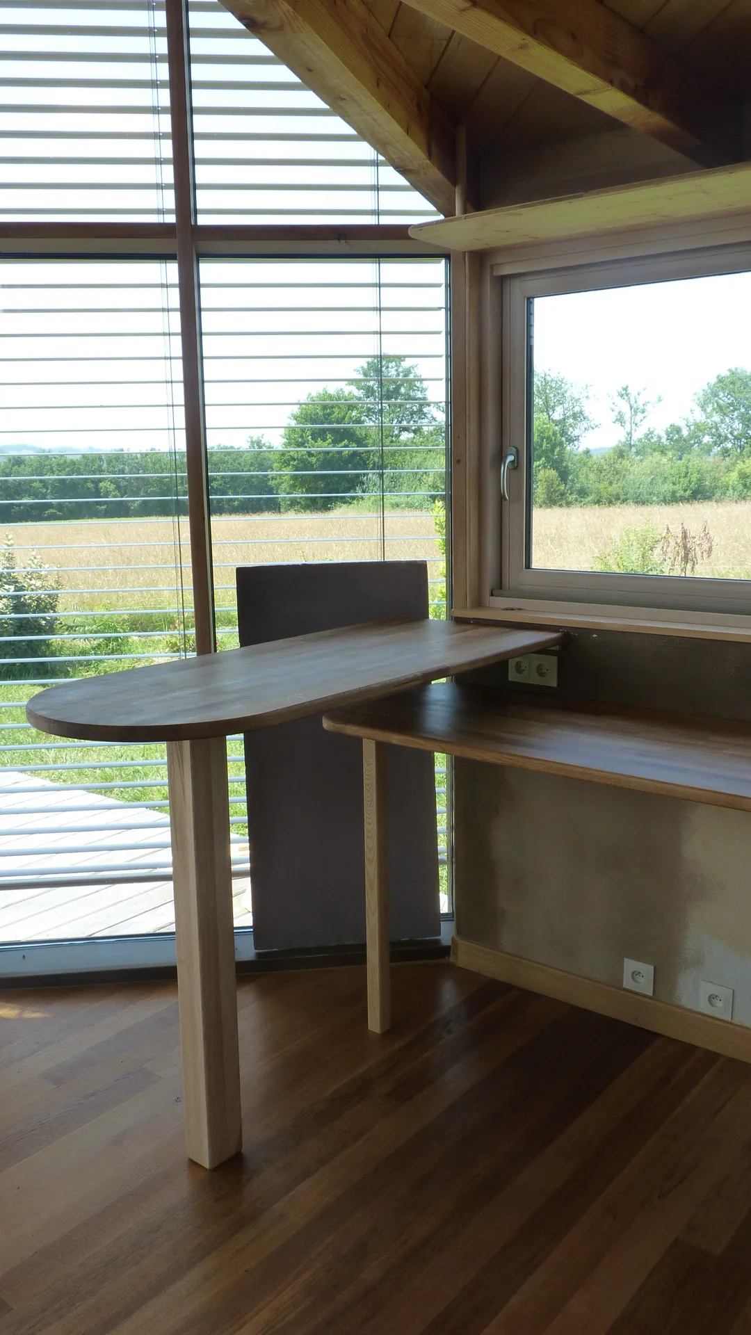 The rounded bar-height table on its solid ash leg, in front of the glazed door