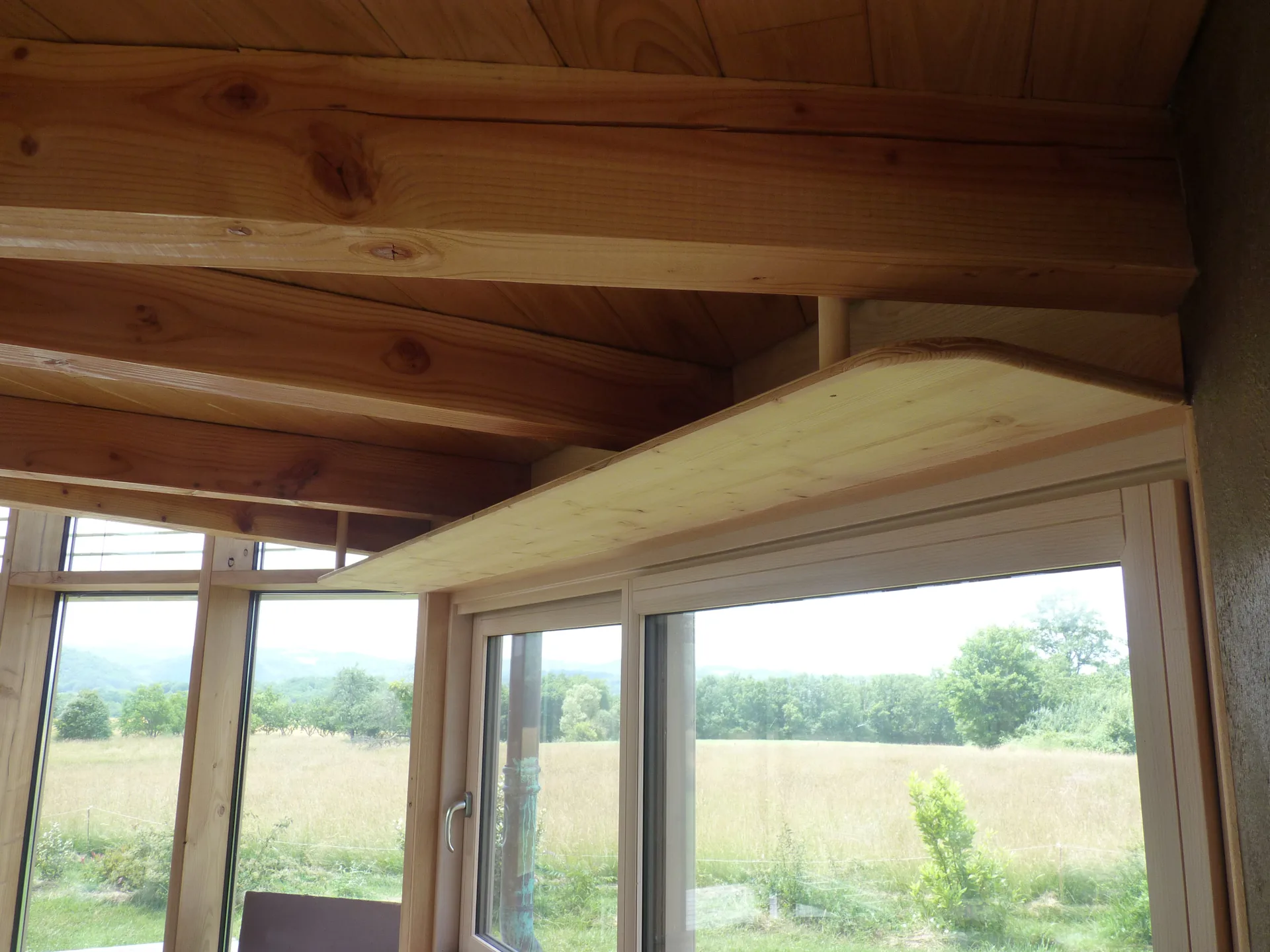 A three-ply spruce shelf scribed between the roof timbers and the wall, above the window