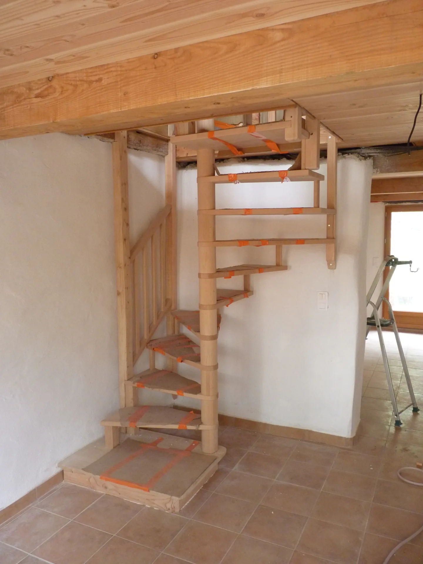 The beech spiral staircase fitted, adapted between the tiled floor and the wooden ceiling