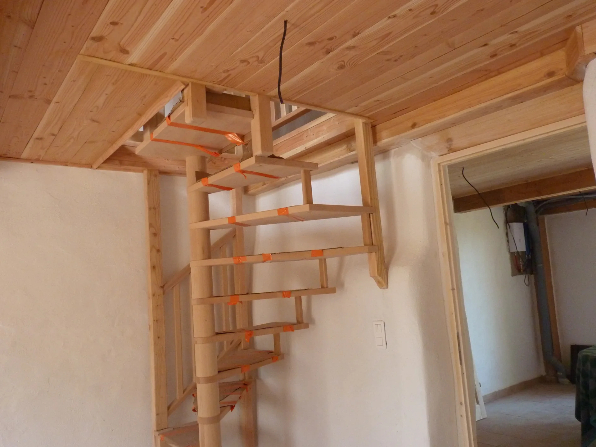 The top of the spiral staircase adapted under the timber ceiling, the door in the background