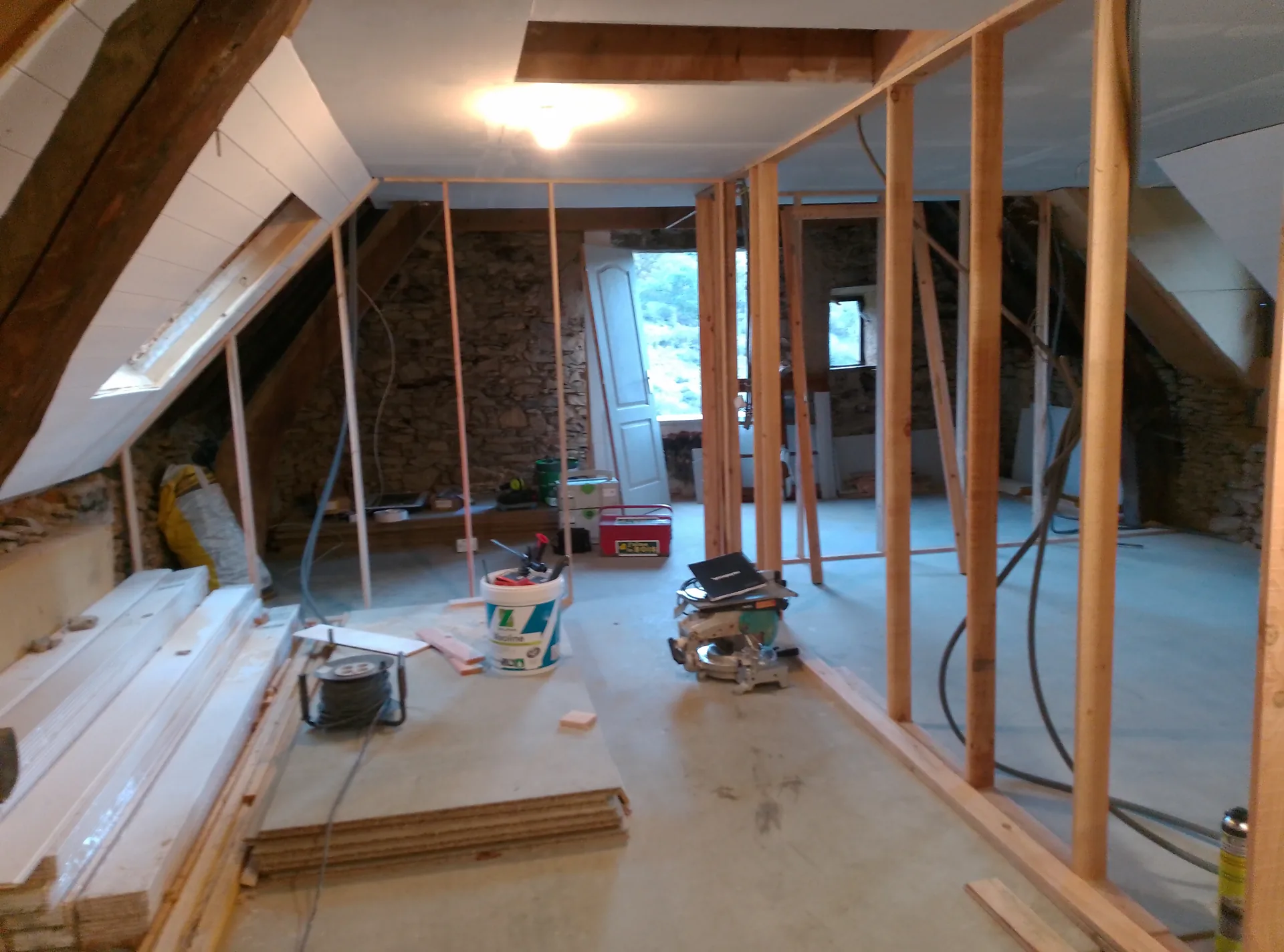 The upstairs floor mid-conversion: timber stud partitions under the insulated roof slopes