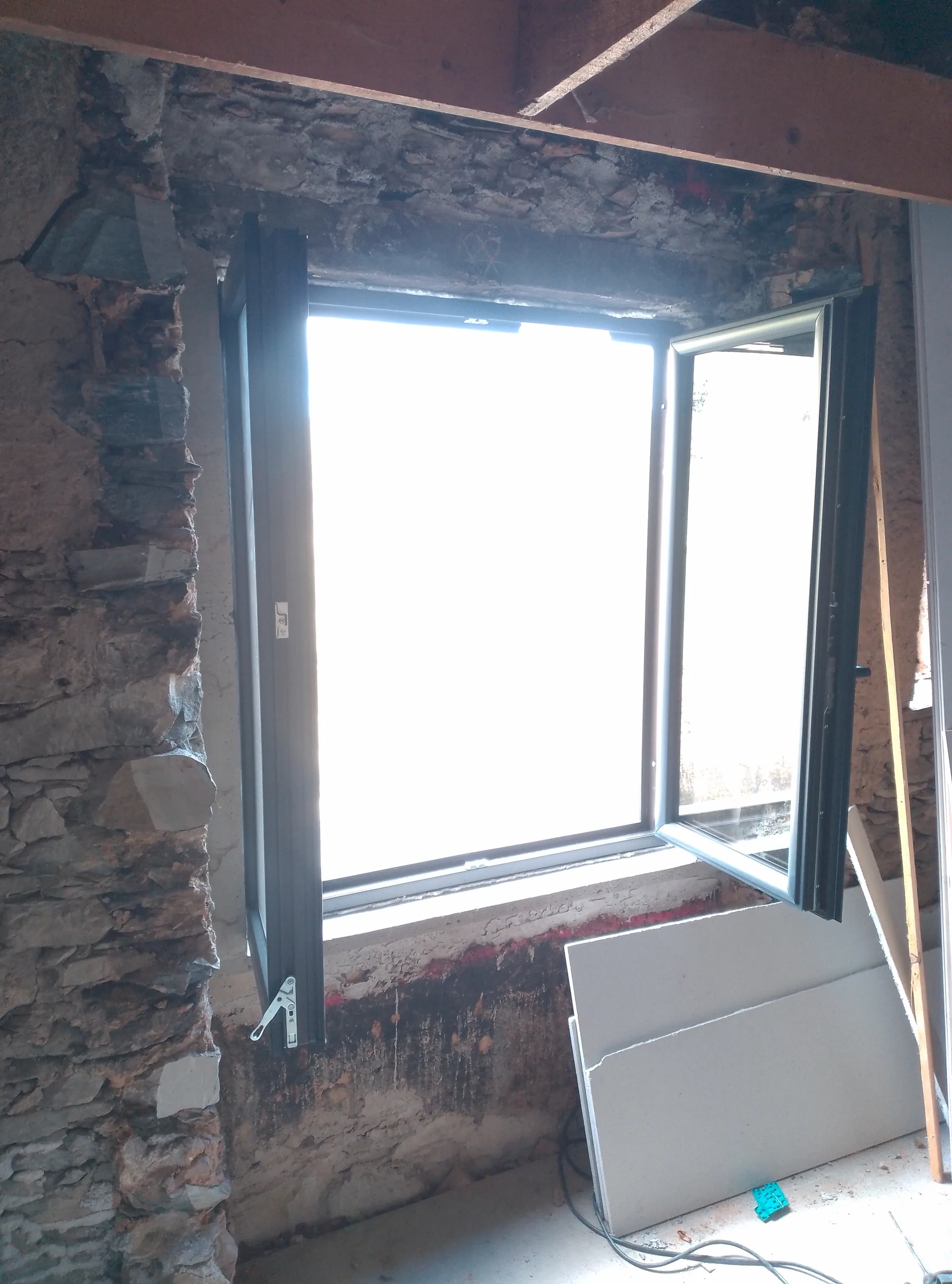 Anthracite grey uPVC window fitted in the stone wall, during the works