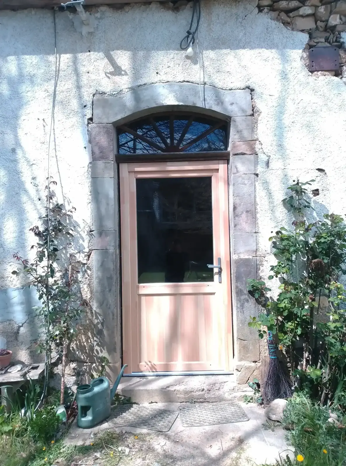 After: the new pine front door, under the same sunburst fanlight