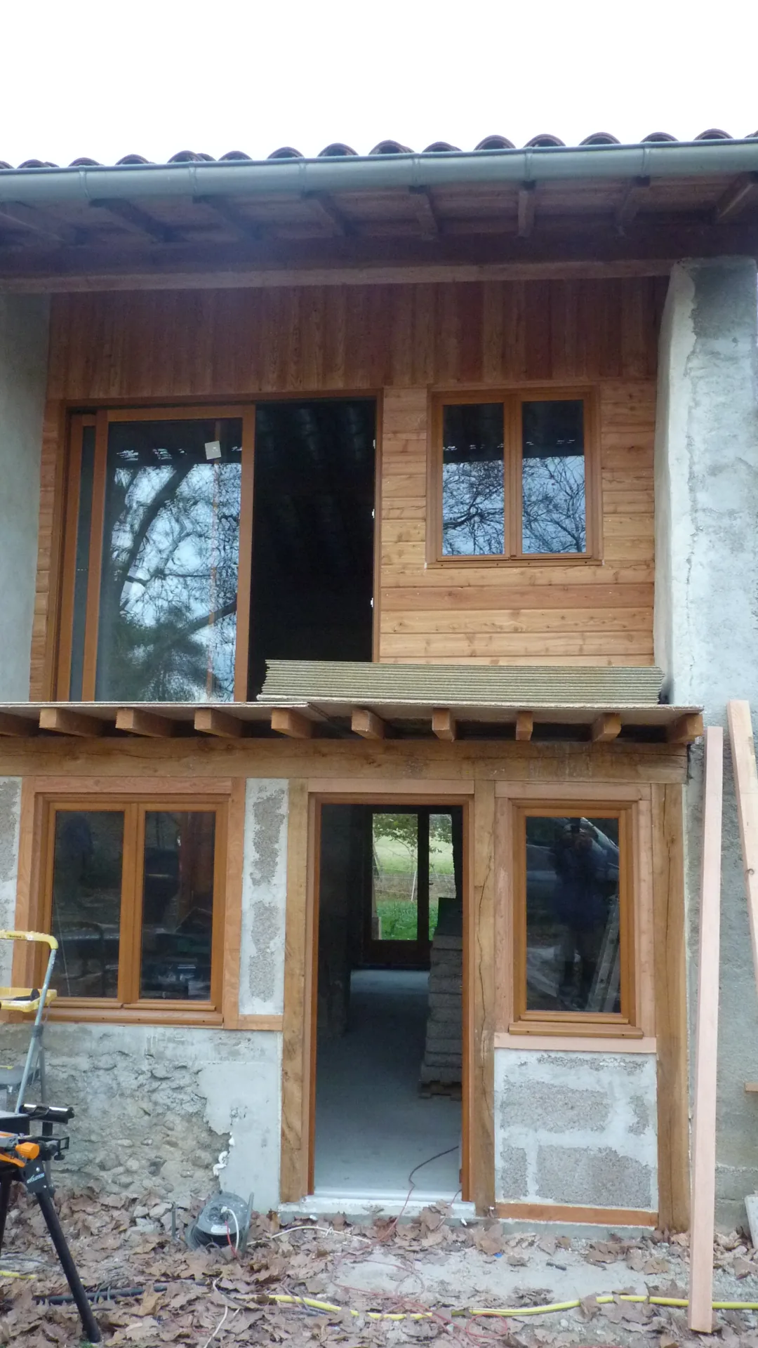 The frontage face on: upstairs windows on the new cladding, French door on the ground floor, balcony joists