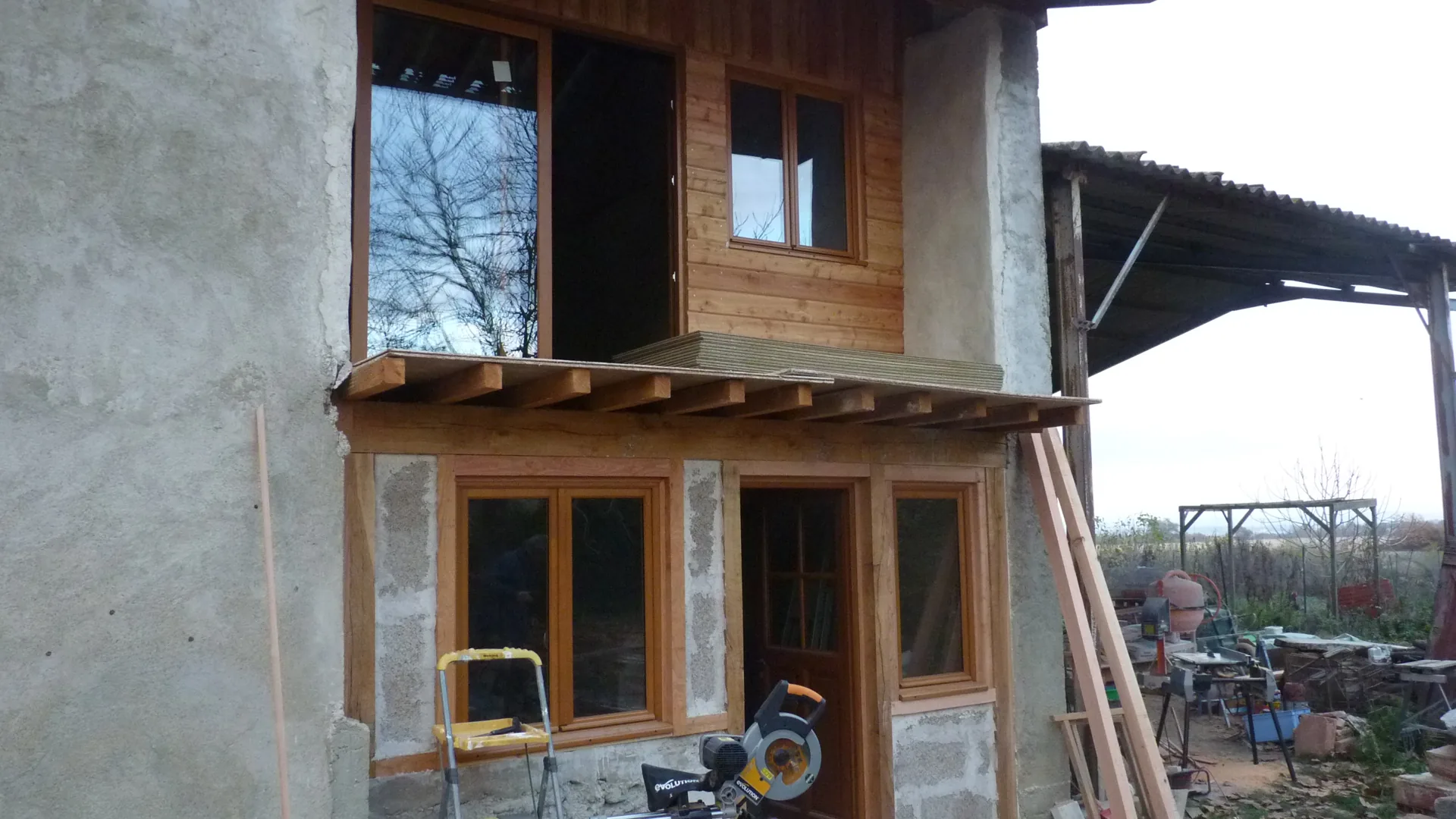Fitting under way: pine windows and doors in place, mitre saw at the foot of the frontage