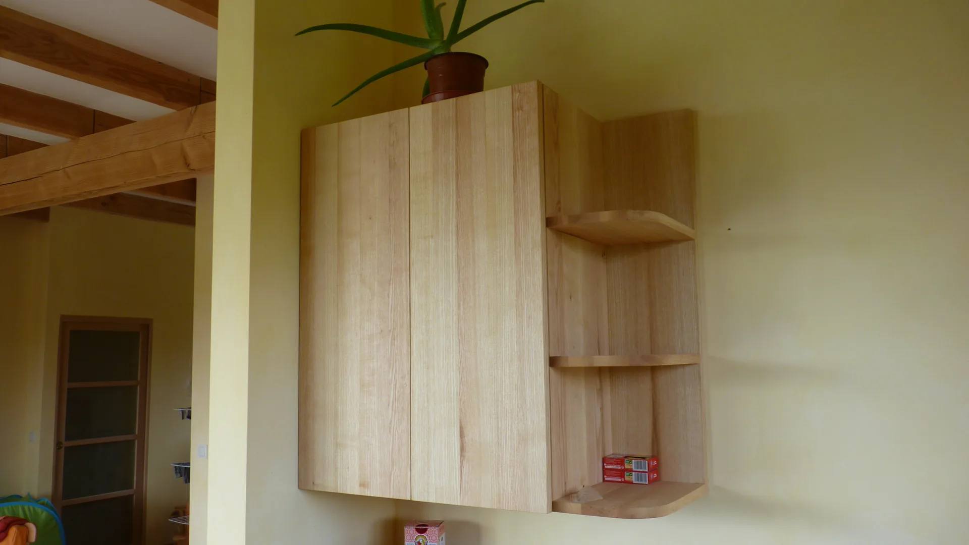A wall cabinet closed: handle-free ash fronts, small rounded shelves on the side