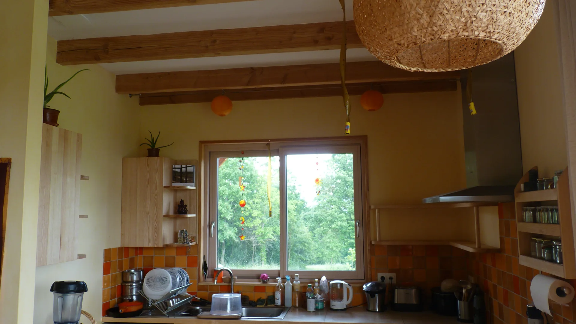 The kitchen seen as a whole: ash wall cabinets either side of the window, exposed beams