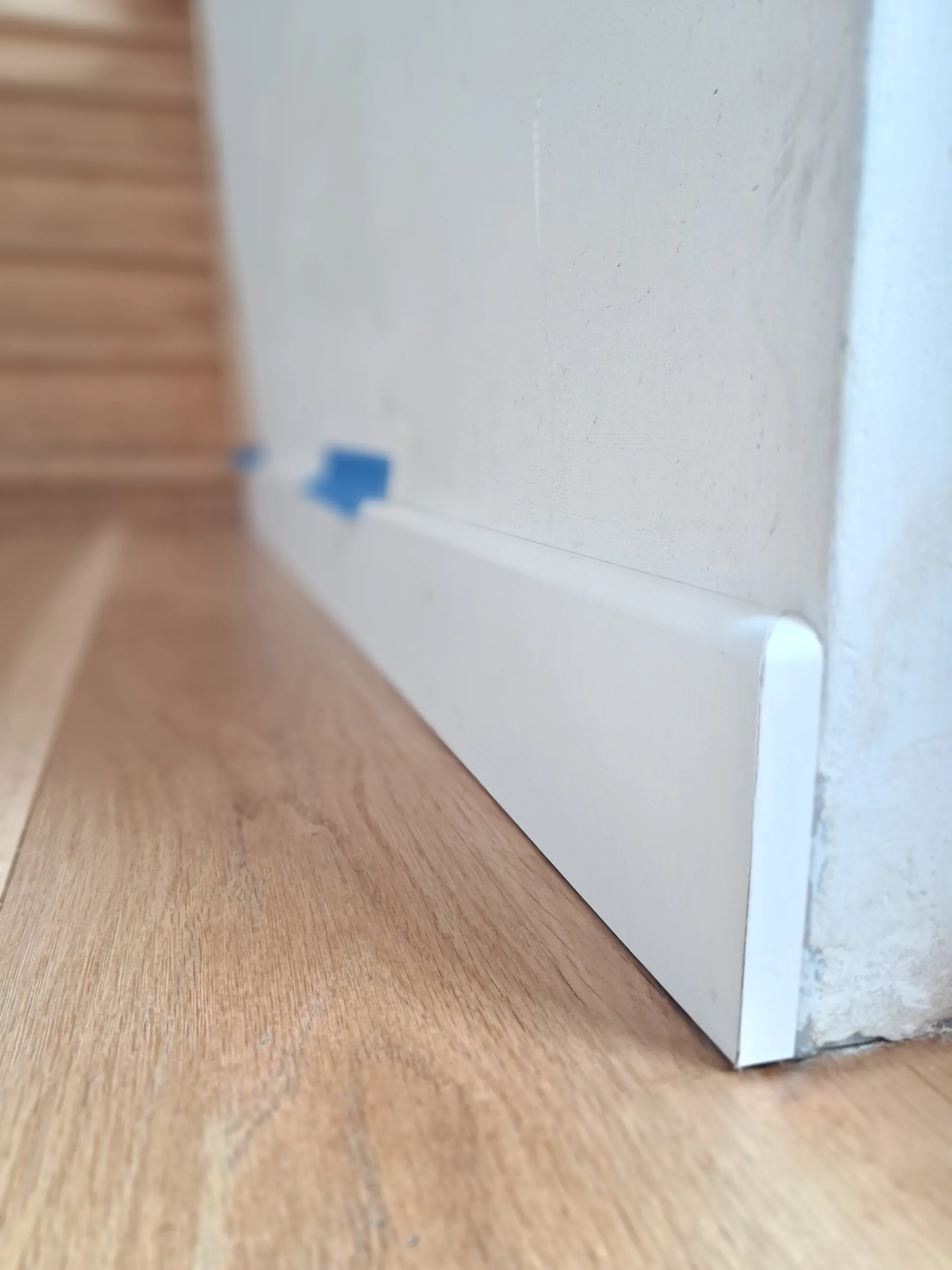 New 14 mm pre-painted white MDF skirting board, expansion gap restored