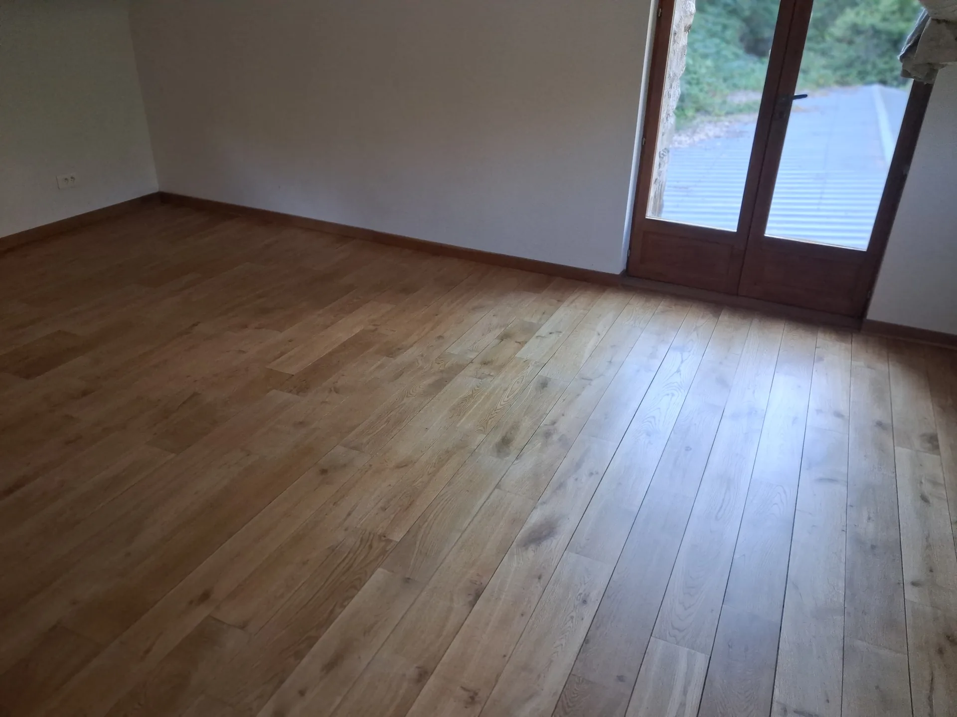 The finished oak floor in front of the french window of an upstairs bedroom