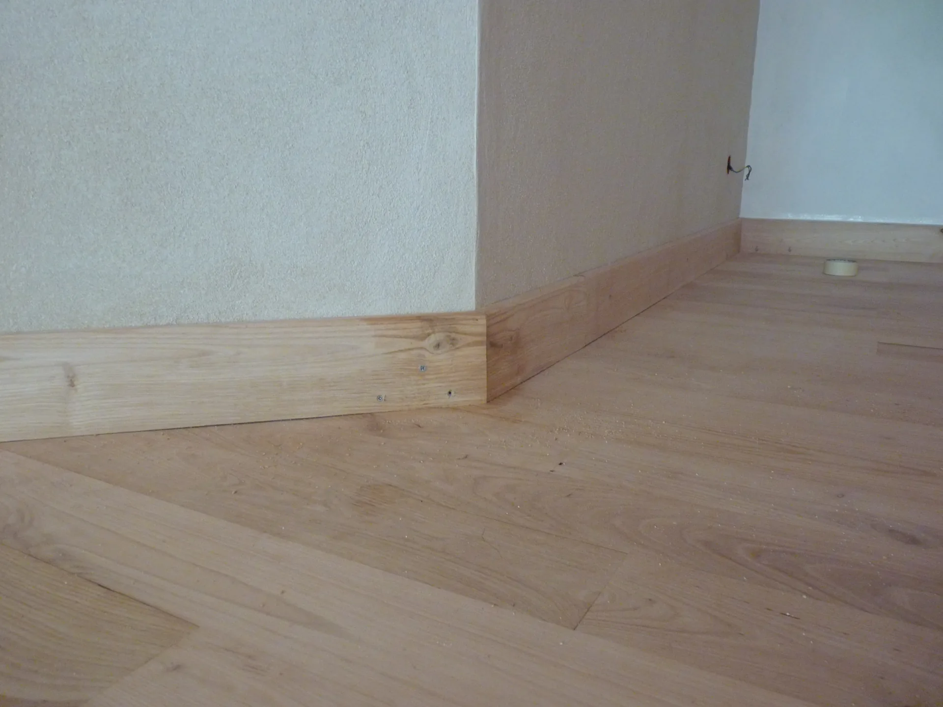 The sweet chestnut skirting box scribed against the uneven wall, in the corner of the room