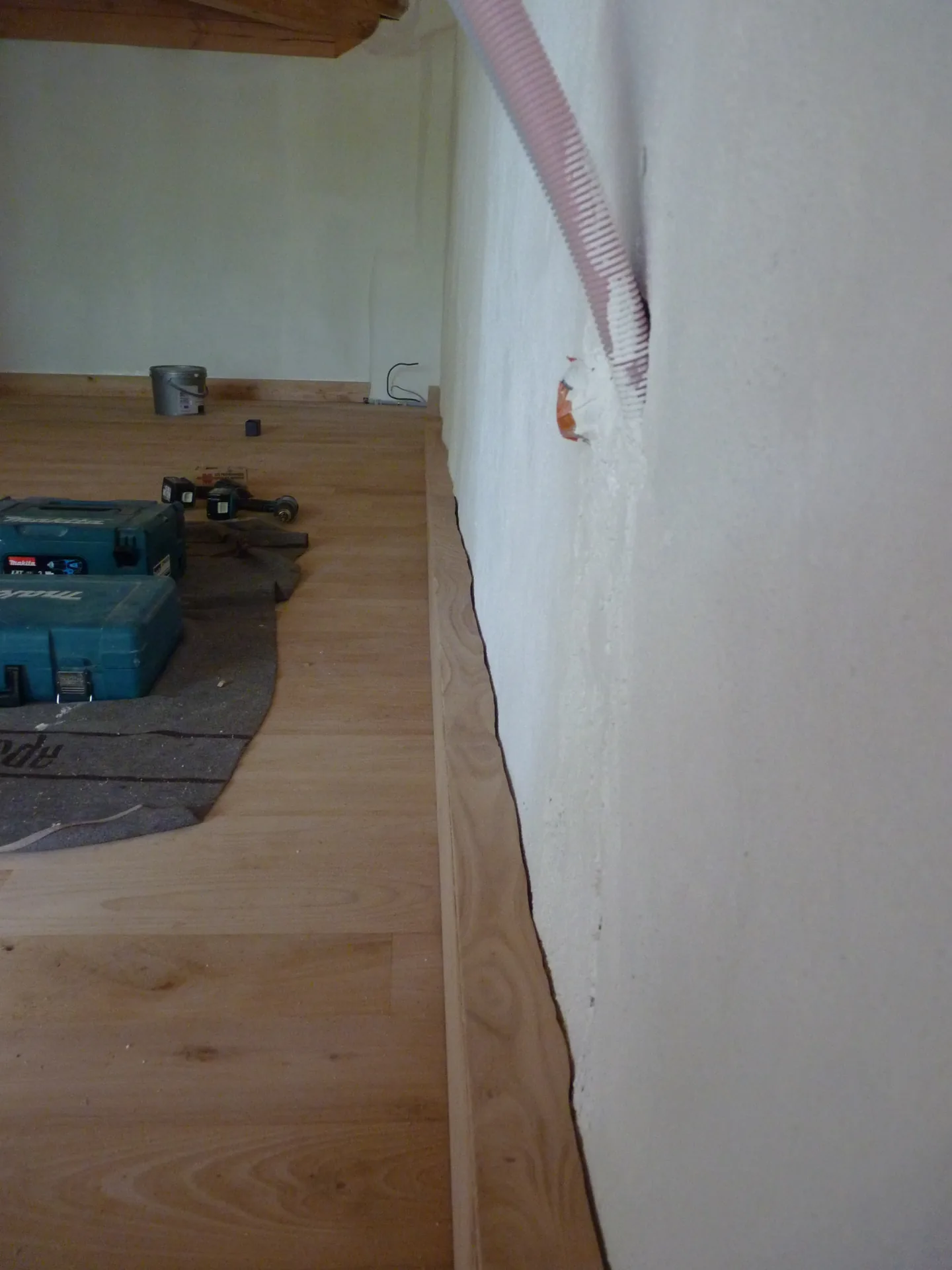 A conduit emerging from the wall at the level of the hollow skirting being fitted