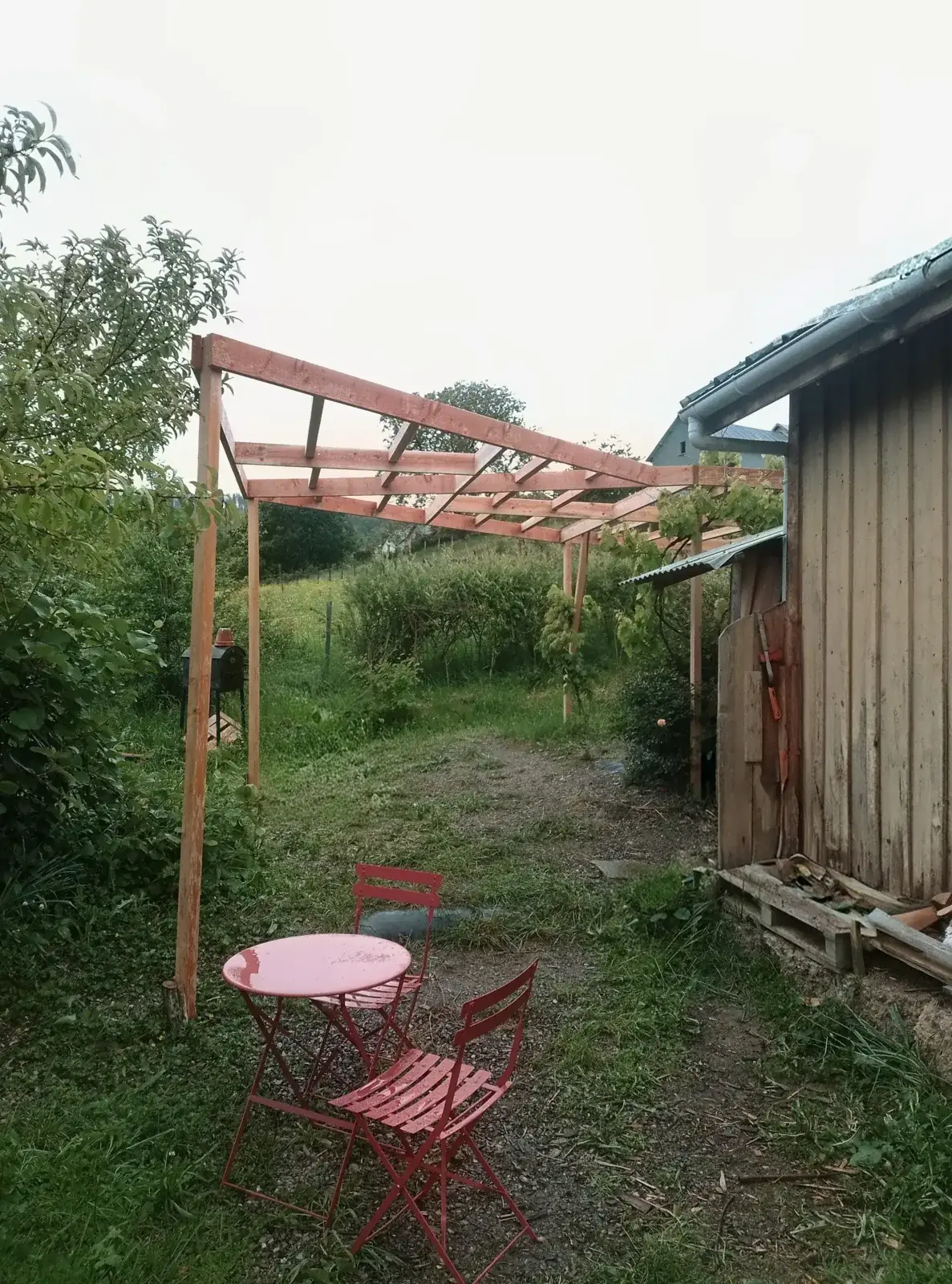Douglas fir pergola following the slope of the land, with garden furniture