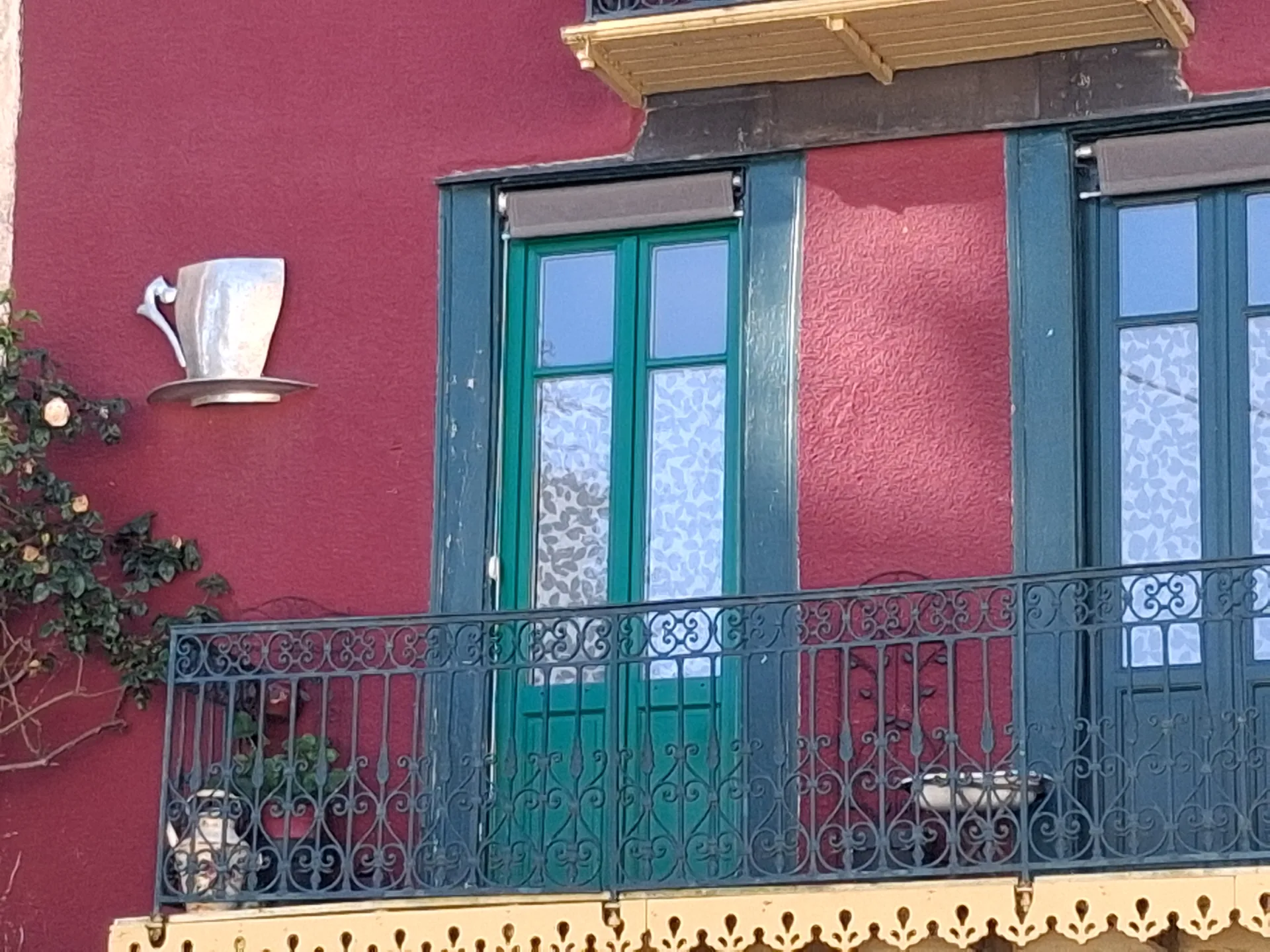 The raspberry façade of the tea room, with the new green French doors upstairs, behind the wrought iron balcony