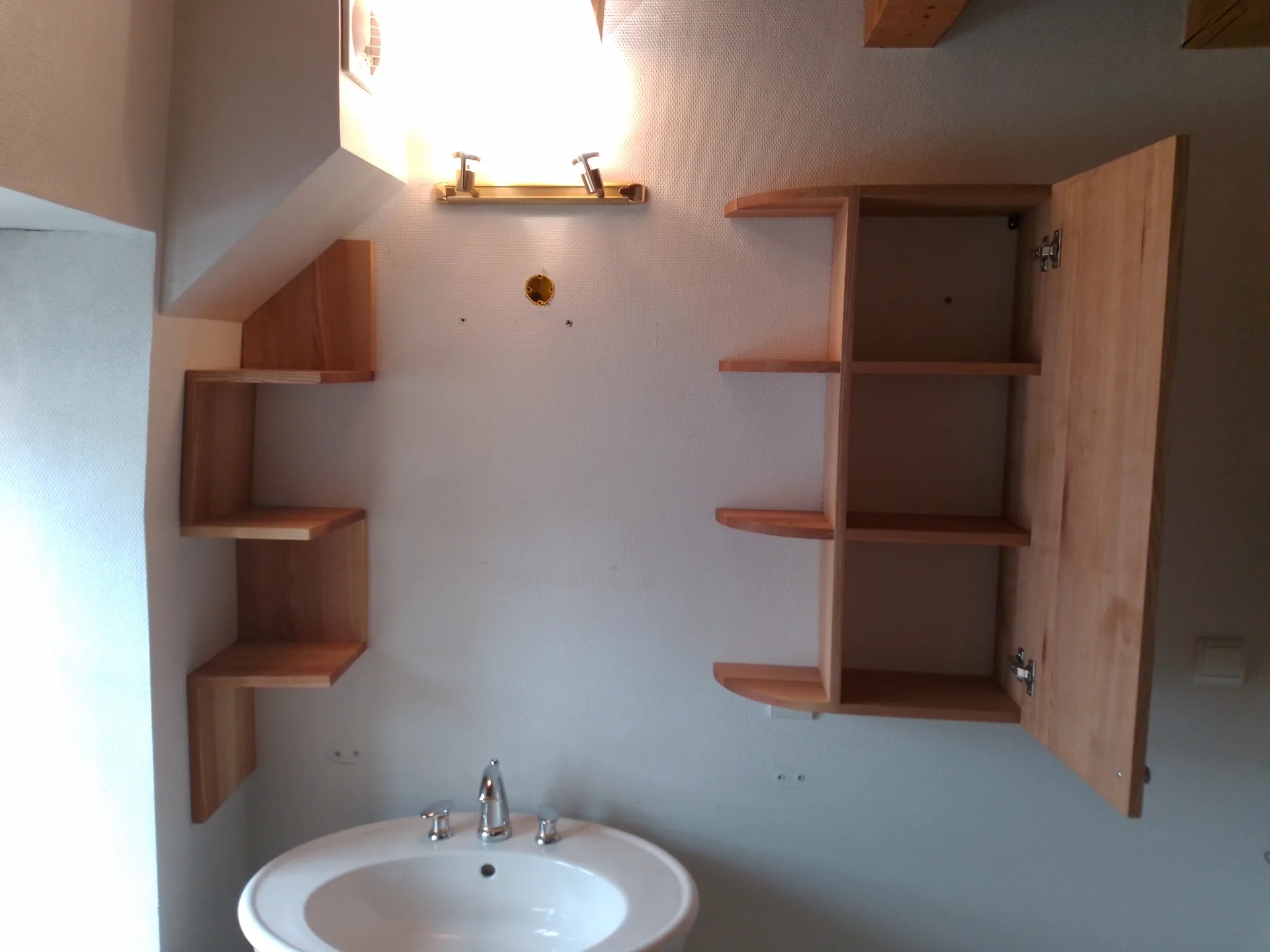 The open wall cabinet and the stepped ash shelf unit, above the pedestal basin