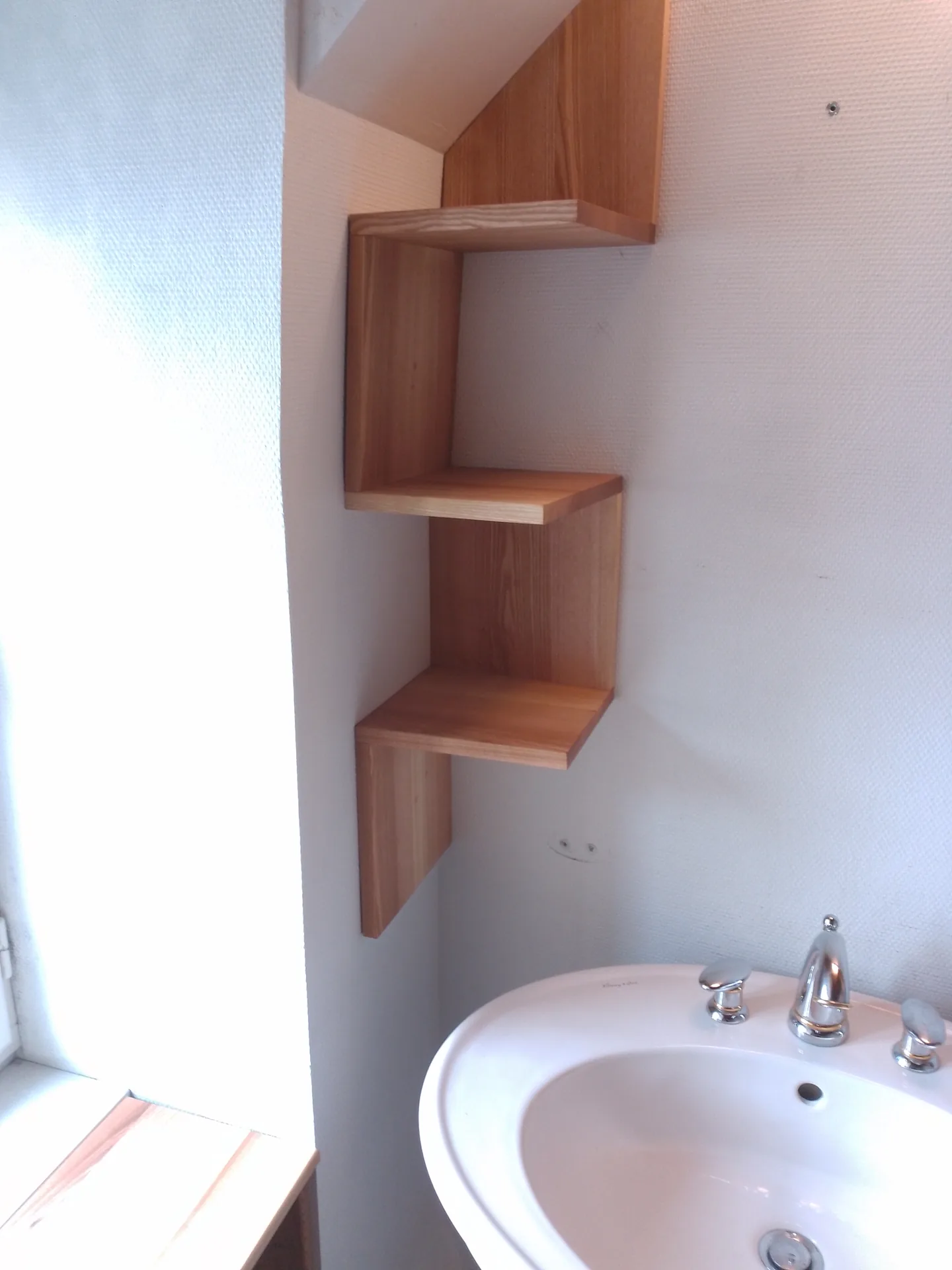 The stepped ash shelf unit, between the window and the pedestal basin