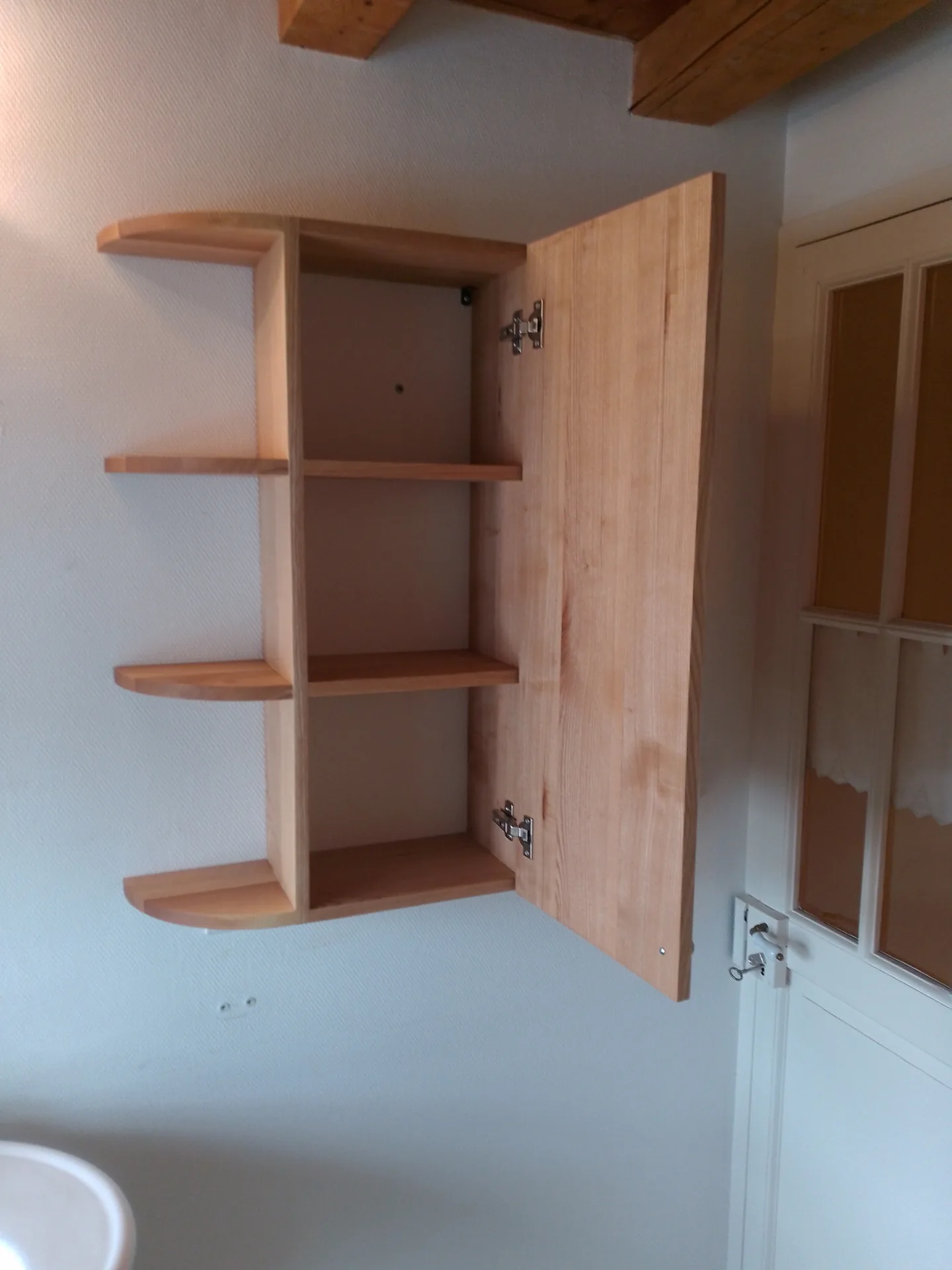 The wall cabinet open: two inner shelves, open shelving running towards the wall