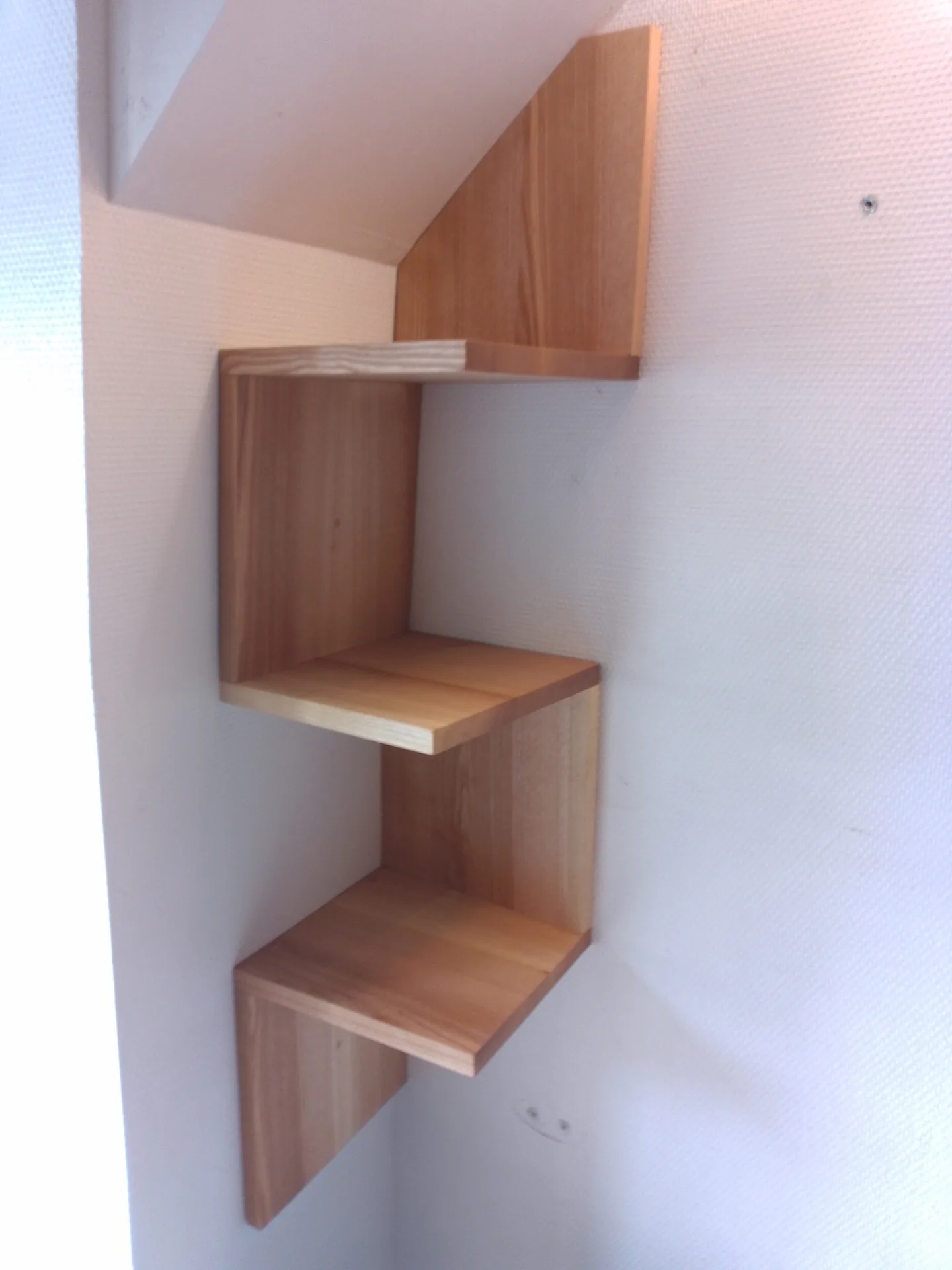 Detail of the stepped shelf unit: solid ash panels and shelves, cuts scribed to the wall